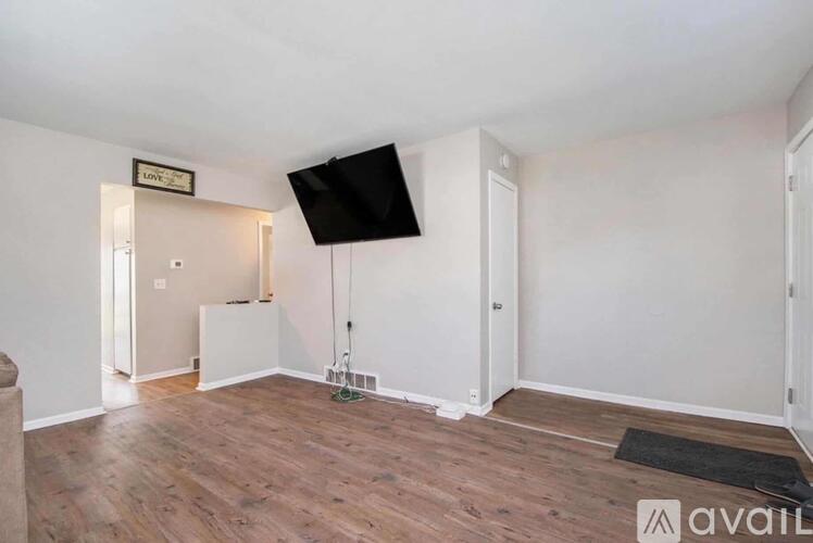 A room with a wooden floor and a flat screen TV mounted on the wall.