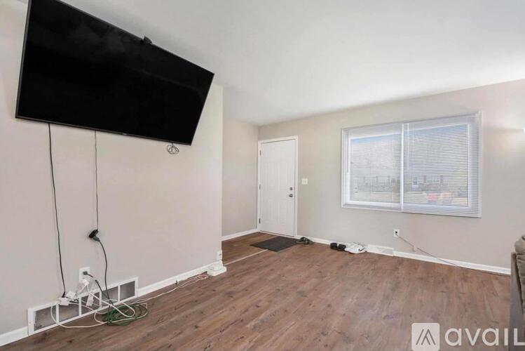A room with a flat screen TV mounted on the wall and a window with blinds.