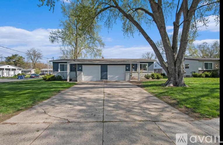 A house with a driveway and a tree in front.