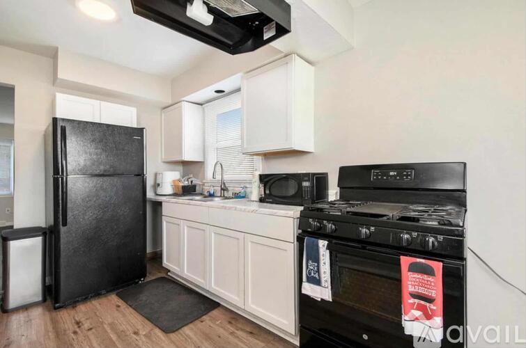 A black fridge and stove in a kitchen with white cabinets.