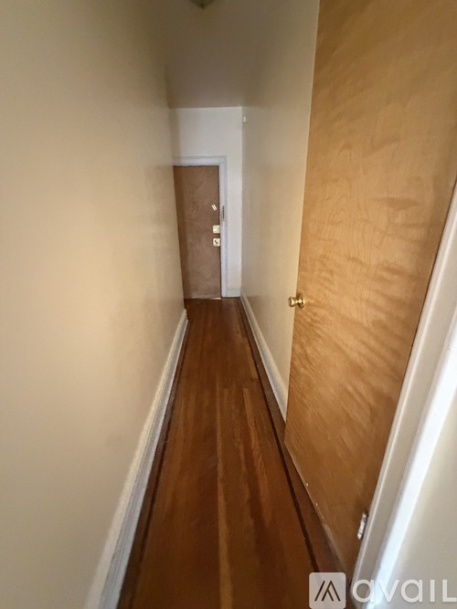A long hallway with a wooden floor and white walls.