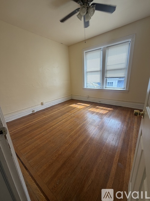 A room with a ceiling fan and a window with blinds.