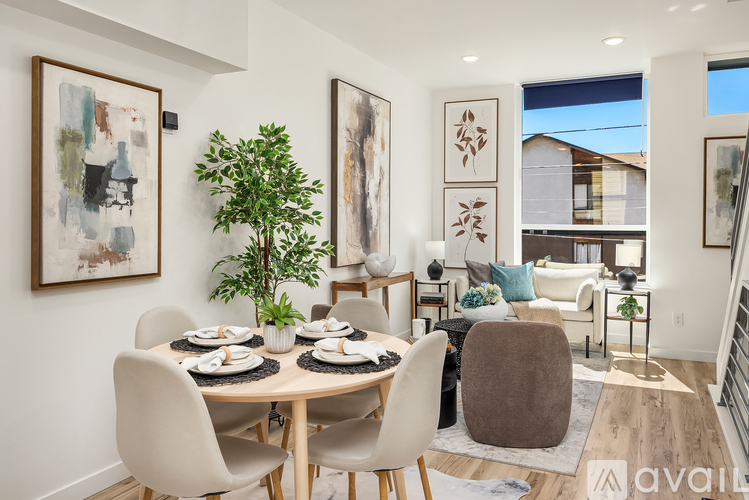 A dining room with a table set for four and a couch in the background.