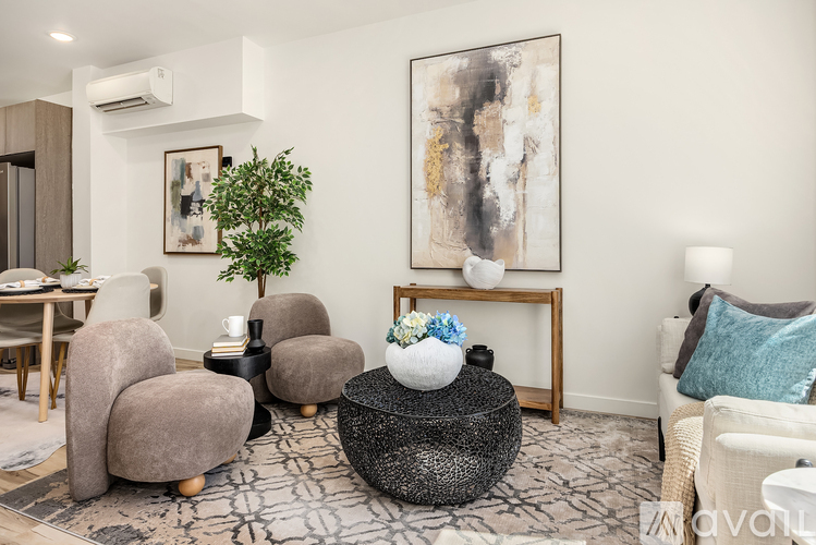 A living room with a grey sofa, a coffee table with a vase of flowers, and a painting on the wall.