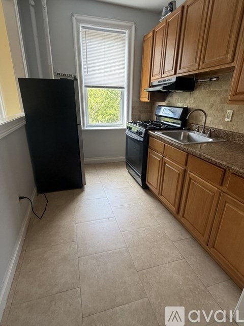 A kitchen with wooden cabinets and a black refrigerator.