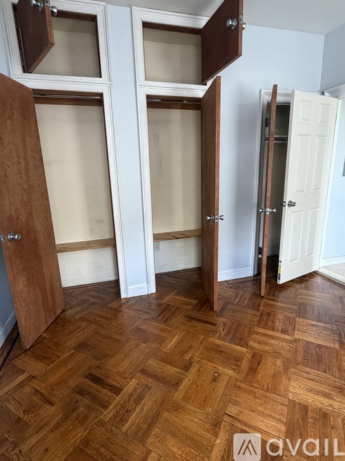 A room with wooden floors and three open wardrobes.
