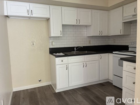 A kitchen with white cabinets and a black countertop.