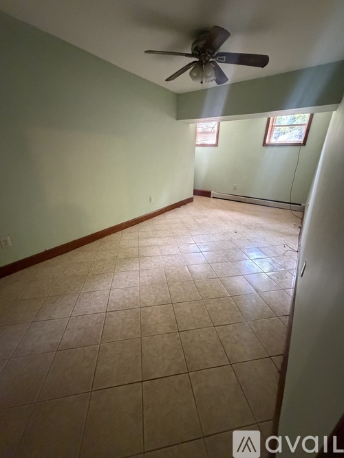 A room with a ceiling fan and tile flooring.