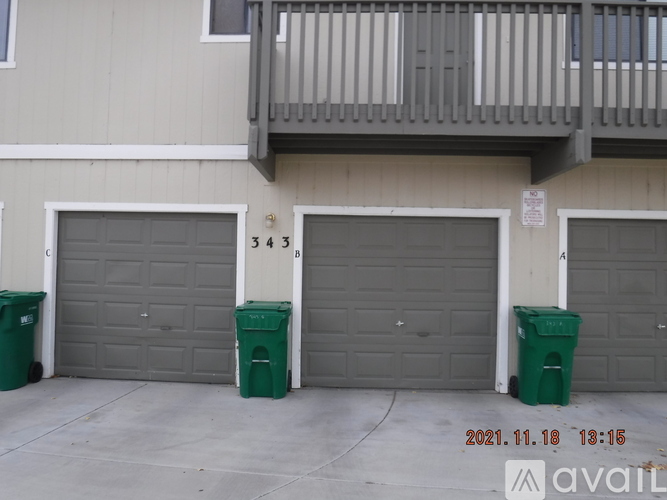 A building with three garage doors and two green bins in front of them.