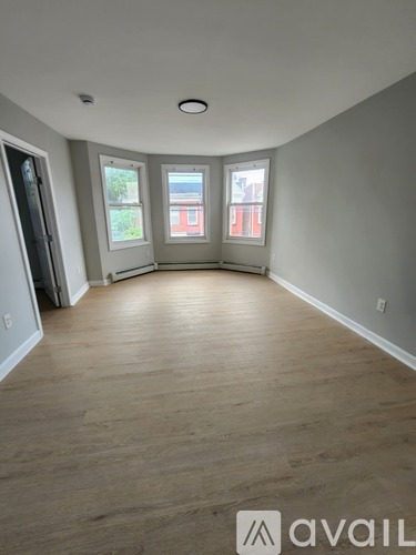 A room with wooden flooring and a window overlooking a red building.