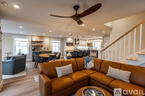 A living room with a brown couch and a ceiling fan.