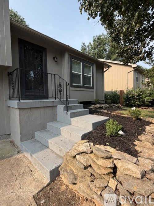 A house with a grey front porch and a stone wall.