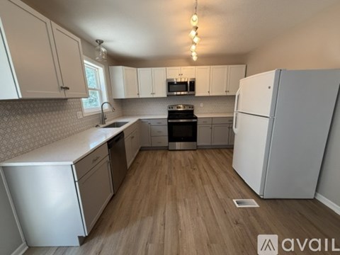 A kitchen with white cabinets and a wooden floor.