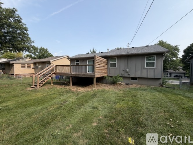 A grassy area with a house and a carport in the background.
