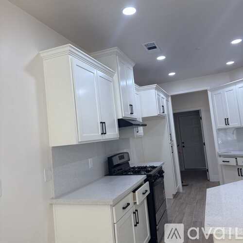 A kitchen with white cabinets and a stove top oven.
