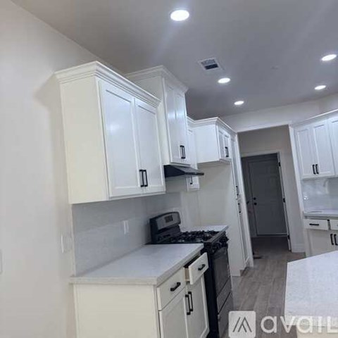 A kitchen with white cabinets and a stove top oven.