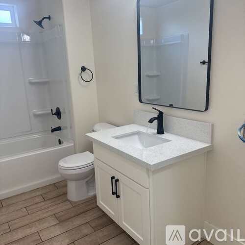 A white bathroom with a toilet, sink, and mirror.
