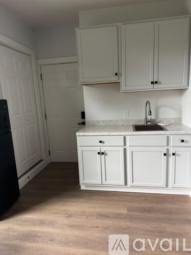 A kitchen with white cabinets and a black refrigerator.