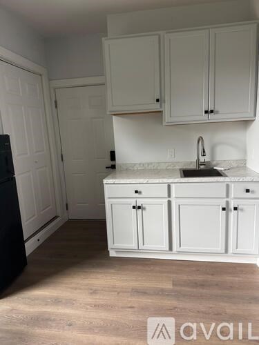 A kitchen with white cabinets and a black refrigerator.