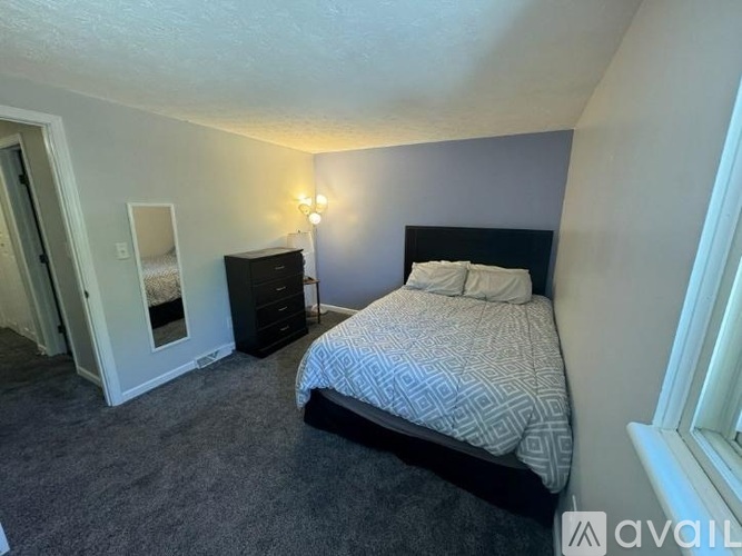 A bedroom with a bed, nightstand, and lamp.