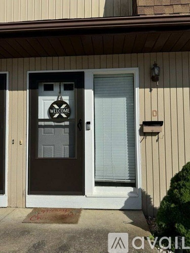 A house with a brown door and a welcome mat on the front porch.