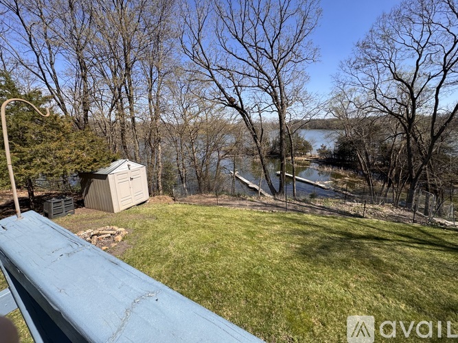 A view from a balcony overlooking a grassy area, trees, and a body of water.