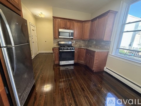A kitchen with wooden cabinets and a stainless steel refrigerator.