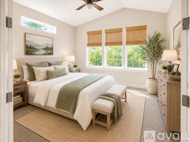 A bedroom with a large bed and a ceiling fan.