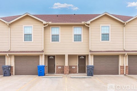 A row of houses with garages and blue bins in front.