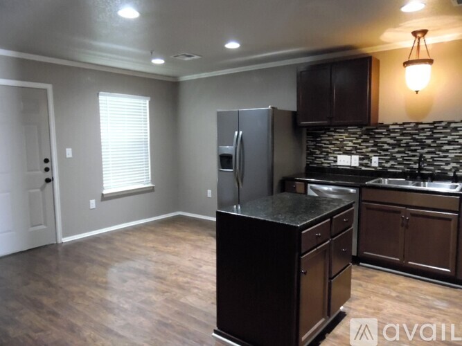 A kitchen with a black countertop and a black fridge.