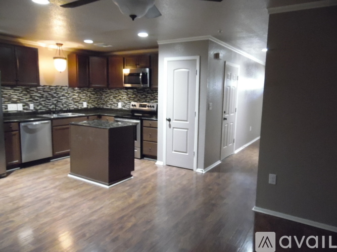 A kitchen with a dark wood floor and a counter top with a sink.