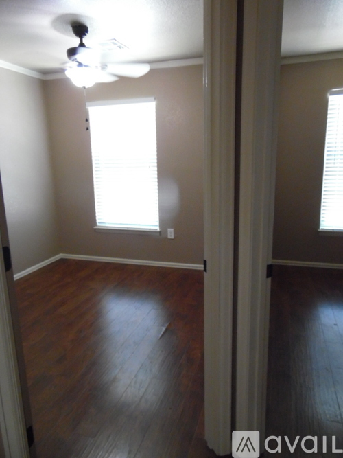 A room with wooden floors and a window with blinds.