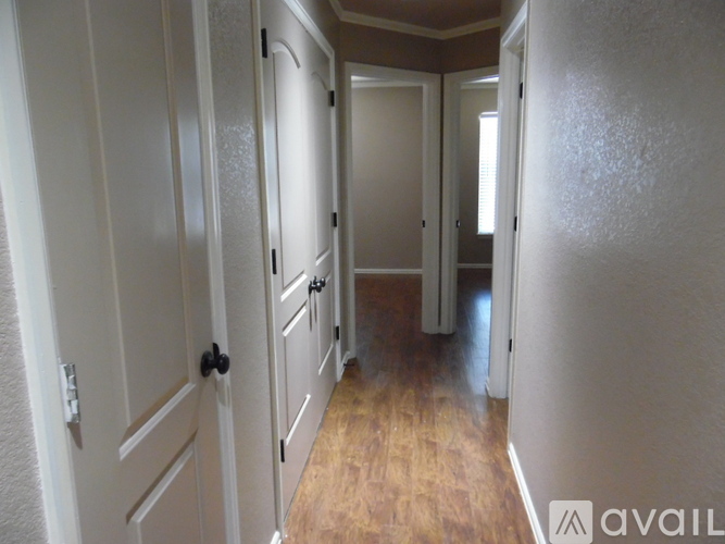 A long hallway with white doors and wooden floors.