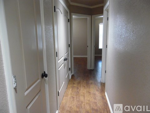 A long hallway with white doors and wooden floors.