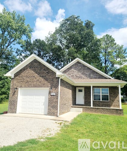 A brick house with a white garage door and a driveway in front.