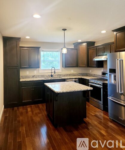 A kitchen with dark wood cabinets and a marble island.