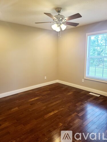 A room with a ceiling fan and wooden flooring.