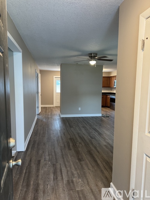A long hallway with wood floors and a ceiling fan.