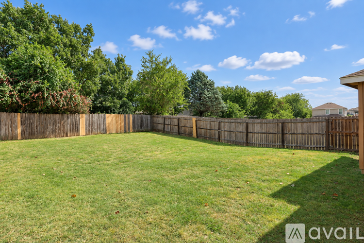 A backyard with a wooden fence and a grassy area.