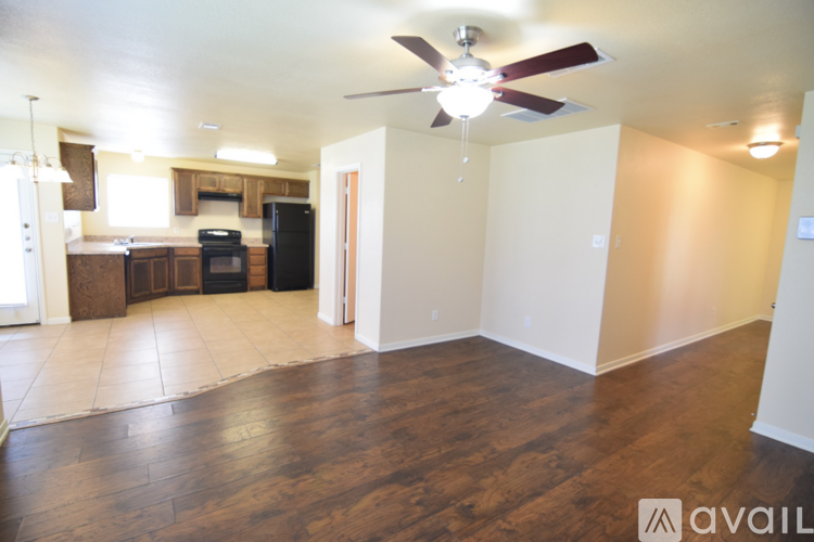A spacious living room with a kitchen in the background and a wood floor.