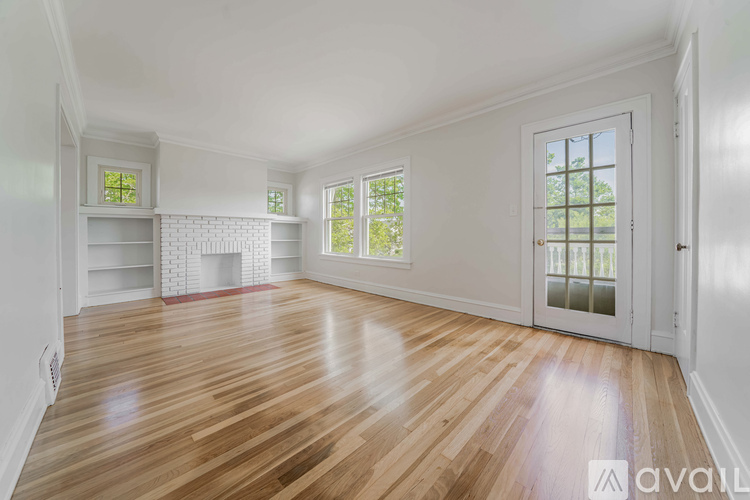 A room with wooden floors and white walls, with a fireplace and built-in shelves.