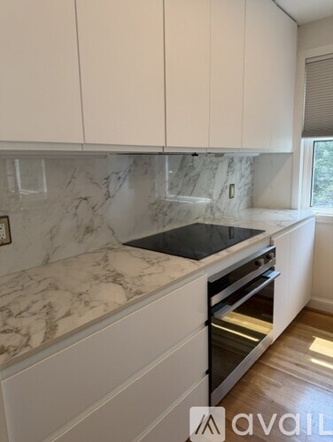 A kitchen with white cabinets and marble countertops.