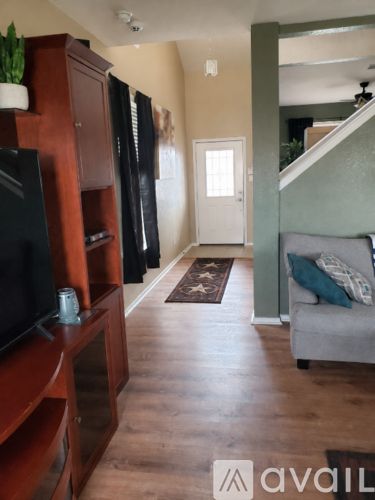 A living room with a grey couch and a wooden entertainment center.