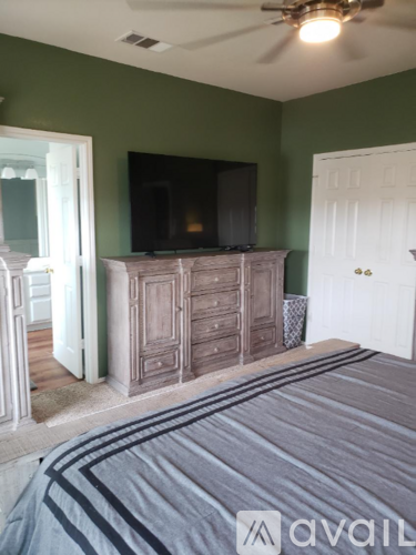 A bedroom with a bed, dresser, and television.