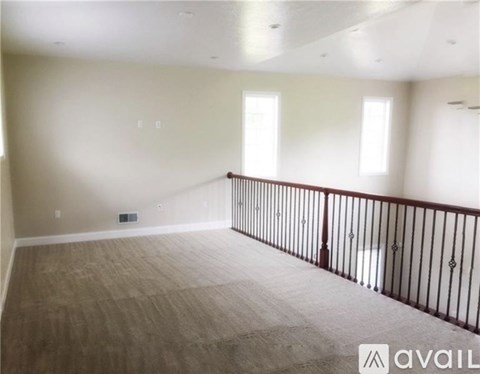 A spacious room with a balcony and hardwood flooring.