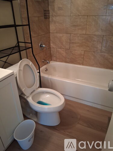 A toilet is installed in a bathroom with a tub and a towel rack.