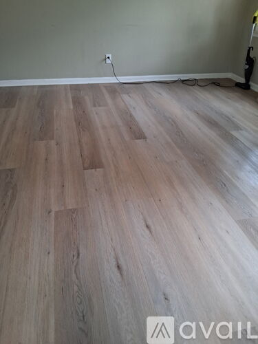 A room with a wooden floor and a vacuum cleaner.