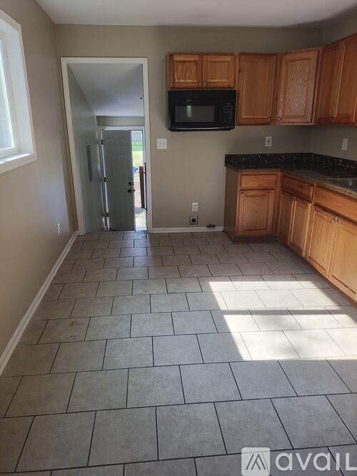 A kitchen with wooden cabinets and a black microwave.