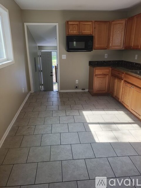 A kitchen with wooden cabinets and a black microwave.