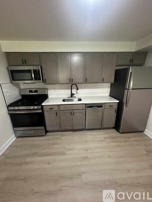 A kitchen with a stove, sink, and refrigerator.